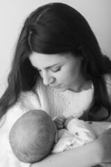 neonato in braccio alla mamma. mamma che lo culla per addormentarlo.