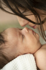 ritratto di neonato e sua mamma, entrambi occhi chiusi, nasi molto vicini quasi che si sfiorano. la mamma sta annusando il profumo del suo neonato